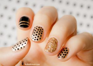 Short oval nails with gold glitter, black and beige polka dots, textured finish, playful design.