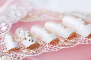 Medium length oval nails with white base and gold accents.