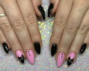 V-shaped stiletto nails, long, black and pink with cat face accent, glossy, feline-inspired design.