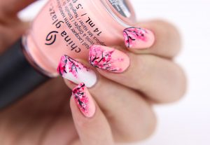 Almond-shaped, medium length, pink and white palette, glossy finish, floral nail art, elegant style.