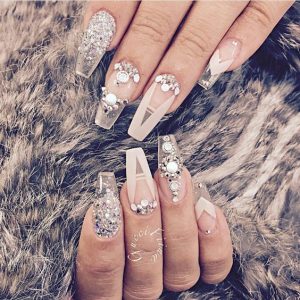 Long stiletto nails with cream, silver, and glitter.