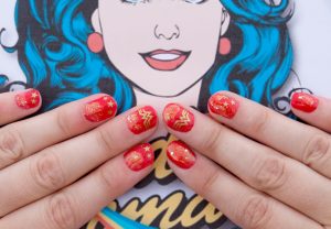 Red nails with gold star and zigzag nail art, glossy finish, almond shape, medium length.