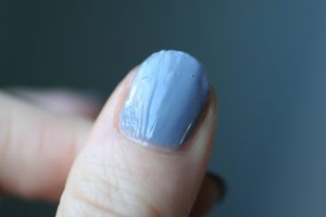 Close-up of a blue almond-shaped nail with a glossy, marbled finish.