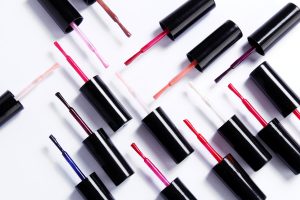 Colorful nail polish bottles with brushes and spilled polish on white background.