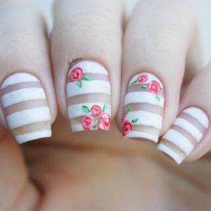 White and beige striped nails with pink roses and green leaves.