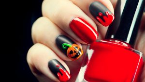 Dark matte black and bright red nails with Halloween accents.