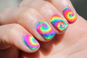 Vivid rainbow swirl nail art on short, square nails with glossy finish and bright colors.