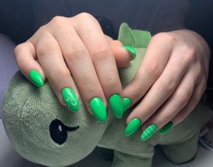 Vibrant green matte nails with swirl and plaid accents, oval shape, short length, trendy design.