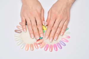 Short, square-shaped nails with a glossy finish in pastel pink, beige, white, and lavender, featuring minimalist design elements and soft colors for a feminine style.