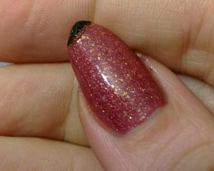 Glittery red with gold accents, short oval shape, glossy finish, festive style.