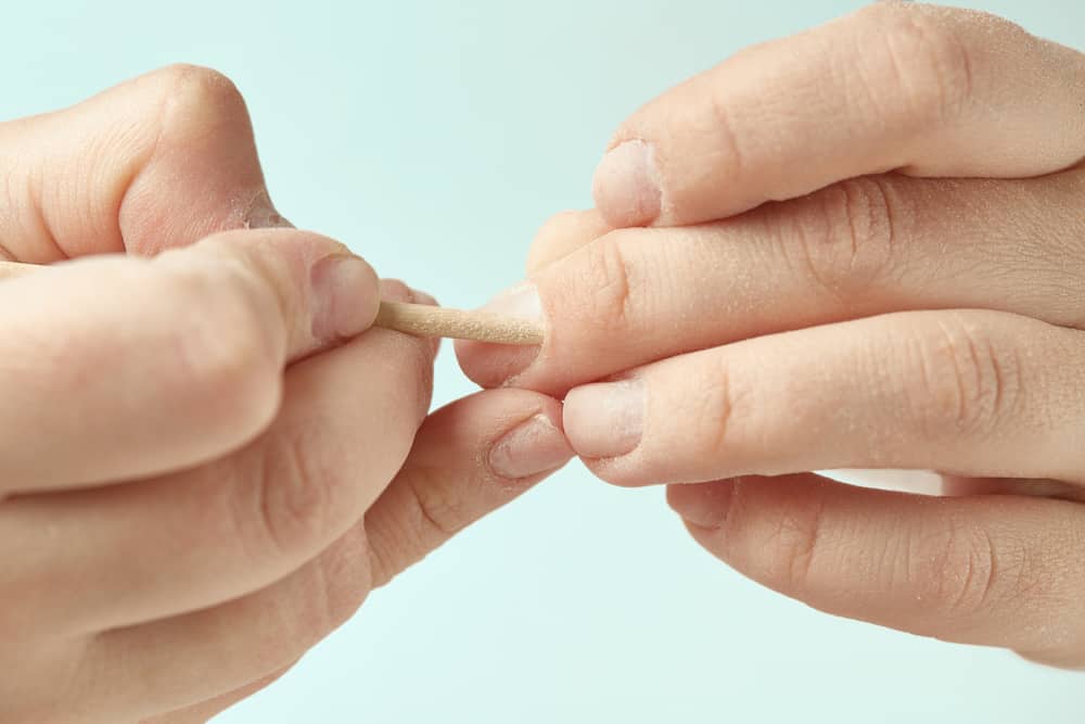 using orange stick to remove glue from nails