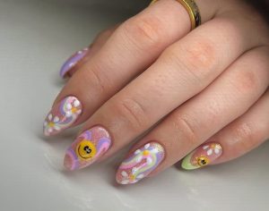 Colorful pastel nail art with floral accents and smiley faces, glossy finish.