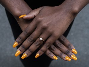 Vibrant orange oval nails with glossy finish, minimalist design, natural skin tone.