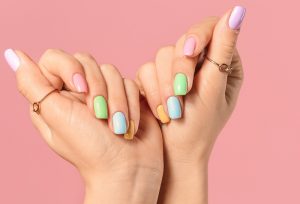 Short almond-shaped nails with pastel colors, glossy finish, playful design style, featuring tiny 3D flower accents.