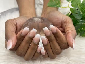 Soft pink-white ombré with glossy finish on almond-shaped, medium-length nails.